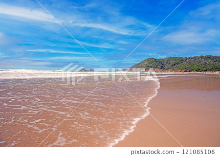 Wide sandy beach on the Golden Coast, Australia, with clear blue skies and gentle ocean waves 121085108