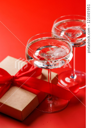 A glasses of champagne elegantly paired with a gift box A glasses of champagne elegantly paired with a gift box 121085951