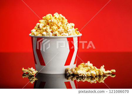 A box of fluffy popcorn against a vibrant red background 121086070