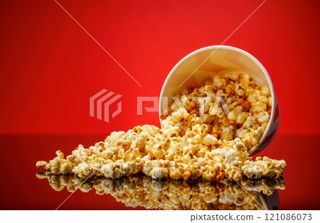 A box of fluffy popcorn against a vibrant red background 121086073