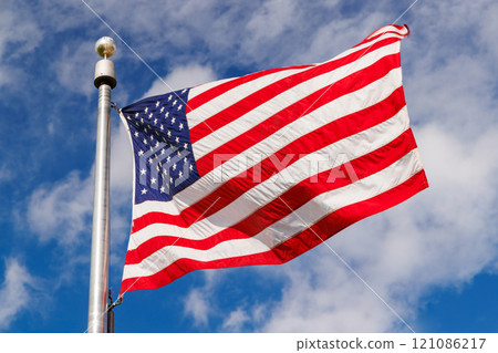 American flag waving against a blue sky 121086217