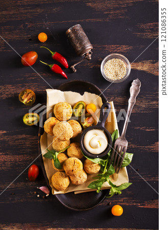 Fork with delicious falafel balls, sauce and vegetables on grunge background Fork with delicious falafel balls, sauce and vegetables on grunge background 121086355