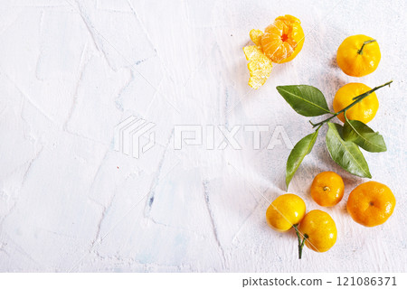 Orange fruit with green leaves on the white wood. 121086371