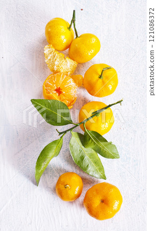 Orange fruit with green leaves on the white wood. Orange fruit with green leaves on the white wood. 121086372
