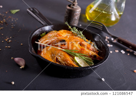 Grilled shrimps with greens and garlic in a pan Grilled shrimps with greens and garlic in a pan 121086547