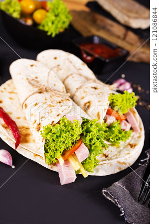 Shawarma sandwich, fresh roll of lavash (pita bread) pork shawarma with ham and cheese 121086844