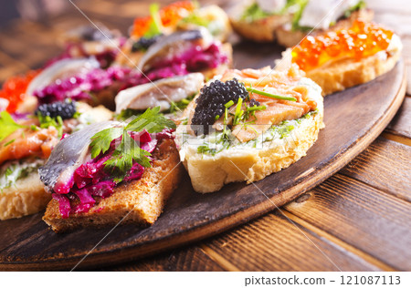 Cocktail canapes with smoked salmon, herring, cream cheese and caviar on rye bread - gourmet party food. Cocktail canapes with smoked salmon, herring, cream cheese and caviar on rye bread - gourmet party food. 121087113