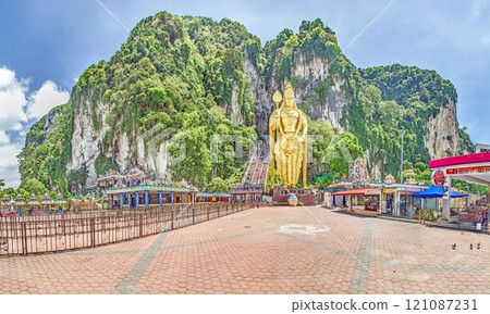 Iconic Batu Caves entrance featuring Lord Murugan golden statue, colorful temple, and limestone cliffs 121087231
