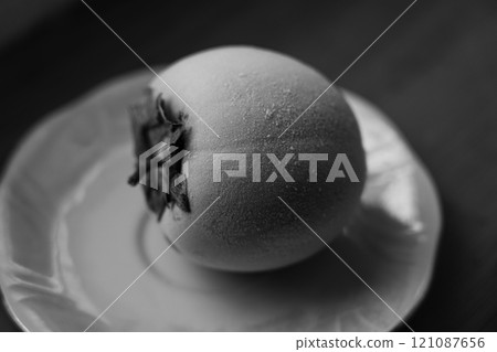 Frozen persimmon on a saucer. Persimmon covered with frost 121087656