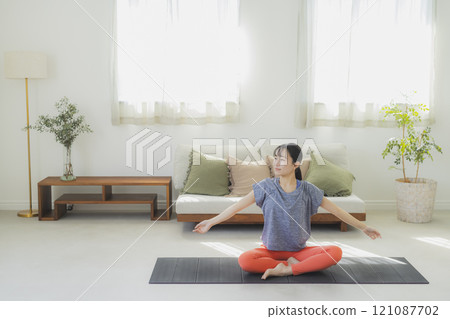 Woman doing yoga in the living room Woman doing yoga in the living room 121087702