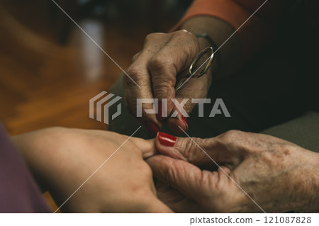 A granddaughter and her grandmother cutting her fingernails 121087828