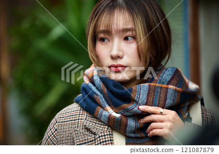 A young woman in winter clothes wearing a scarf holding a smartphone A young woman in winter clothes wearing a scarf holding a smartphone 121087879