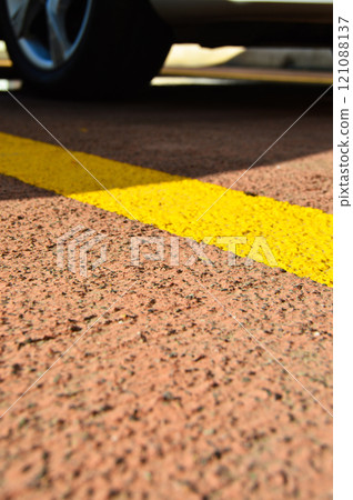 Asphalt concrete road with yellow stripes and car parking area 121088137