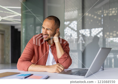 Man holding neck in discomfort at office desk with laptop. Depicts workplace ergonomics, stress, and physical strain. Ideal for illustrating office-related health issues and computer overuse. Man holding neck in discomfort at office desk with laptop. Depicts workplace ergonomics, stress, and physical strain. Ideal for illustrating office-related health issues and computer overuse. 121088550