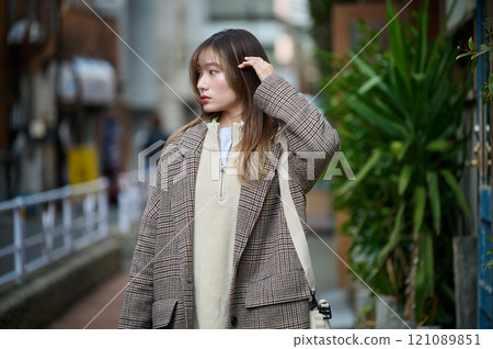 一個長髮的年輕女子穿著外套散步 121089851