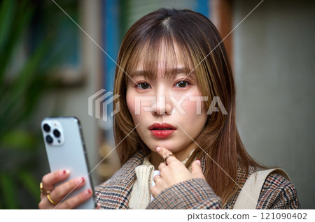 Young woman in winter clothes holding a smartphone 121090402