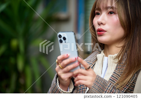 穿著冬衣的年輕女子拿著智慧型手機 穿著冬衣的年輕女子拿著智慧型手機 121090405
