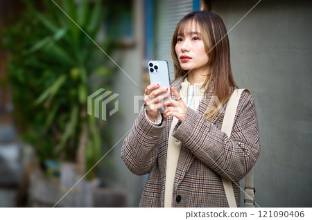 穿著冬衣的年輕女子拿著智慧型手機 穿著冬衣的年輕女子拿著智慧型手機 121090406