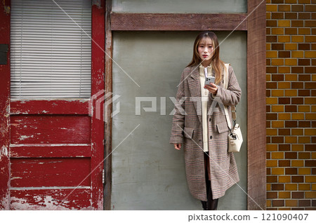 穿著冬衣的年輕女子拿著智慧型手機 穿著冬衣的年輕女子拿著智慧型手機 121090407