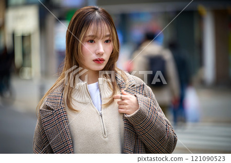 A young woman with long hair wearing a coat taking a walk A young woman with long hair wearing a coat taking a walk 121090523