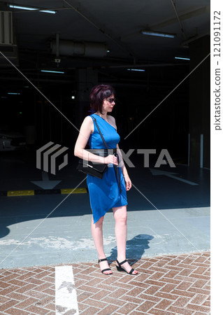 A Stylish Escape: A Woman in a Blue Dress Gracefully Exits an Underground Parking Garage, Embracing the Urban Landscape Above with Confidence and Elegance A Stylish Escape: A Woman in a Blue Dress Gracefully Exits an Underground Parking Garage, Embracing the Urban Landscape Above with Confidence and Elegance 121091172