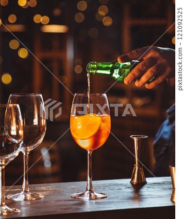 Bartender making aperol spritz cocktail with orange slice on bar Bartender making aperol spritz cocktail with orange slice on bar 121092525