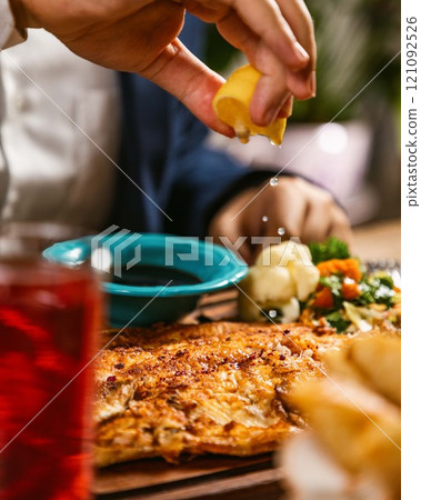Businessman squeezing lemon on delicious fish dish in restaurant 121092526