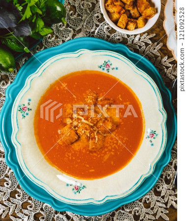 Tomato soup with croutons and grated cheese on a table 121092528