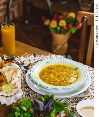 Chicken soup with herbs being served on a table with orange juice 121092529