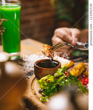 Man dipping grilled chicken into teriyaki sauce at restaurant 121092536