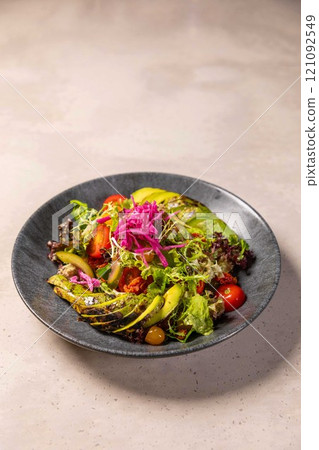 Fresh vegan salad with grilled avocado and tomatoes on concrete background 121092549