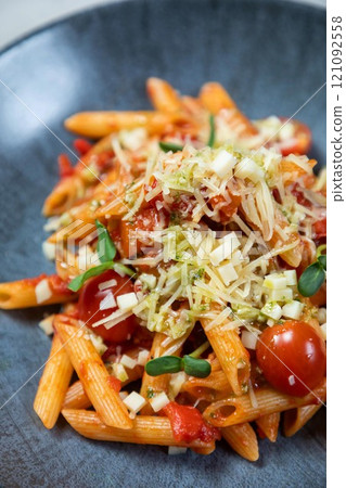 Penne pasta being served with tomato sauce, cheese, and basil Penne pasta being served with tomato sauce, cheese, and basil 121092558