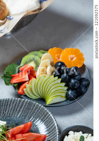 Sliced fruits arranged on a plate, creating a colorful and healthy breakfast option 121092575