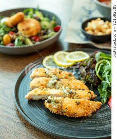 Breaded chicken breast with lemon and salad on restaurant table Breaded chicken breast with lemon and salad on restaurant table 121092589