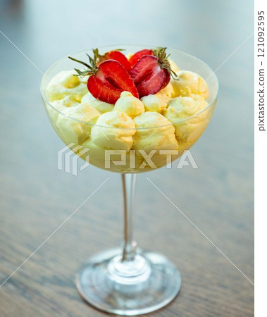 Delicious creamy dessert with strawberries in elegant glass standing on wooden table Delicious creamy dessert with strawberries in elegant glass standing on wooden table 121092595