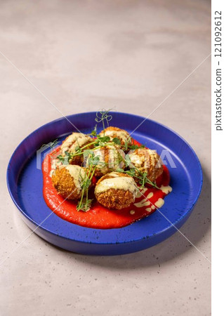 Deep fried arancini balls served on blue plate with sauce and herbs 121092612