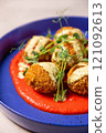 Delicious deep fried arancini rice balls being served on tomato sauce with herbs 121092613