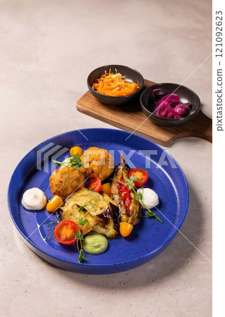 Gourmet vegan dish served on blue plate with side dishes 121092623