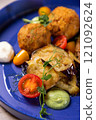 Arancini being served on blue plate with eggplant and tomatoes 121092624