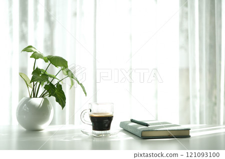 coffee cup and pothos plant pot on white table minimal interior 121093100