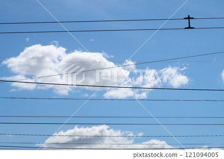 Trolleybus wires against the background of white clouds and blue sky, urban public transport. 121094005