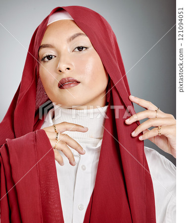 Portrait of a woman wearing a red hijab against grey studio background and copyspace. Young muslim lady wearing a headscarf, posing and showing radiant skin, makeup, eyelash extensions and jewellery Portrait of a woman wearing a red hijab against grey studio background and copyspace. Young muslim lady wearing a headscarf, posing and showing radiant skin, makeup, eyelash extensions and jewellery 121094051