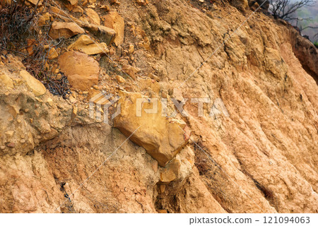 Closeup of crumbling dirt mountainside. Brown textured stone or clay cliff wall. Rough orange mountain environment. Copyspace nature scene for background. Outdoor surface for bouldering and climbing Closeup of crumbling dirt mountainside. Brown textured stone or clay cliff wall. Rough orange mountain environment. Copyspace nature scene for background. Outdoor surface for bouldering and climbing 121094063