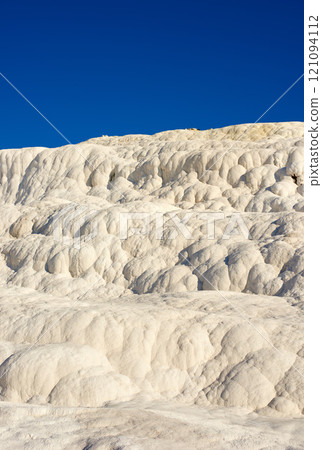 The Travertine pools and terraces in Pamukkale, Turkey. Desert sand with curvy pattern texture against a blue sky. Tourism holiday destination at rock cotton castle location during hot springs 121094112