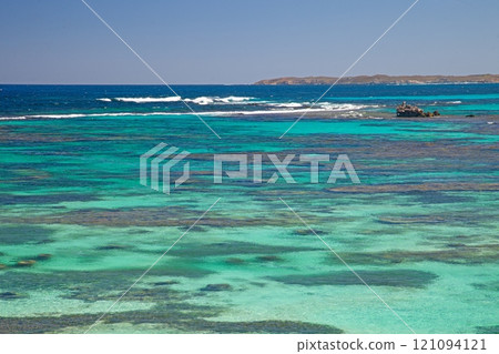 Vivid turquoise ocean waters showcasing coral reefs off Rottnest Island with distant coastline in view Vivid turquoise ocean waters showcasing coral reefs off Rottnest Island with distant coastline in view 121094121