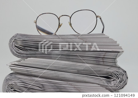 Rolled up stack of fresh newspapers and glasses, news, printed background. Rolled up stack of fresh newspapers and glasses, news, printed background. 121094149