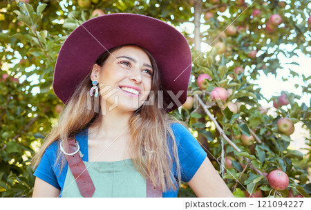 Trendy farm worker wearing a hat daydreaming on a fruit farm during harvest season. Young smiling farmer in front of a apple tree on a sunny day. The agricultural industry growing fresh produce Trendy farm worker wearing a hat daydreaming on a fruit farm during harvest season. Young smiling farmer in front of a apple tree on a sunny day. The agricultural industry growing fresh produce 121094227
