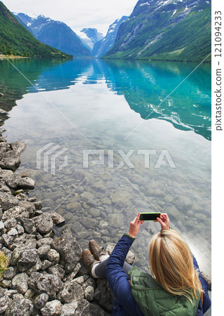 Adventure woman taking photo of beautiful nature mountail lake with smart phone travel explore discover 121094233