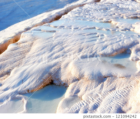 Closeup of travertine pools and terraces in Pamukkale, Turkey. Traveling abroad for vacation and tourism. Cotton castle area with carbonate mineral after flowing thermal spring water from above Closeup of travertine pools and terraces in Pamukkale, Turkey. Traveling abroad for vacation and tourism. Cotton castle area with carbonate mineral after flowing thermal spring water from above 121094242
