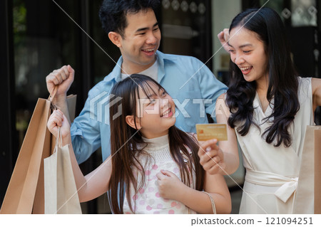 Happy Family Enjoying Black Friday Shopping with Credit Card and Shopping Bags in a Modern Retail Environment Happy Family Enjoying Black Friday Shopping with Credit Card and Shopping Bags in a Modern Retail Environment 121094251